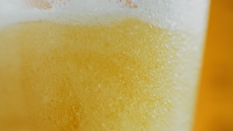 Beer-is-pouring-into-angled-glass.-IPA-on-tap.-Cold-Light-Beer-in-a-glass-with-water-drops.-Craft-Beer-forming-waves-close-up.-Freshness-and-froth.-Bar-background.-Microbrewery-craft-beer.